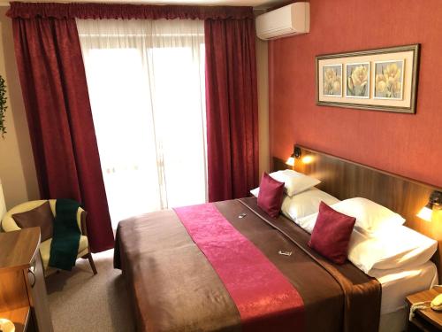 a bedroom with a bed with red walls and a window at Ambrózia Étterem és Panzió in Kazincbarcika