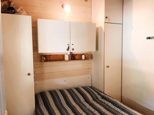 Habitación pequeña con cama y armarios blancos. en Chalet à Gassin au calme sous les pins, en Gassin
