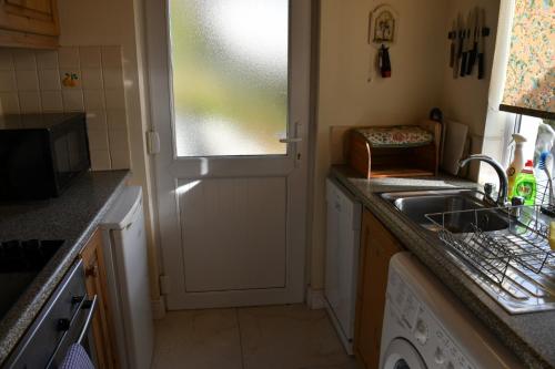 una pequeña cocina con fregadero y ventana en Rocklands Cottage, en Kinsale