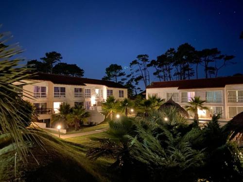 a hotel at night with palm trees and buildings at Punta del Este Arenas Hotel in Punta del Este