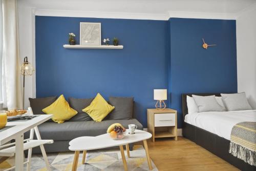 a living room with a couch and a blue wall at Studio Apartment by Homely Stays in London