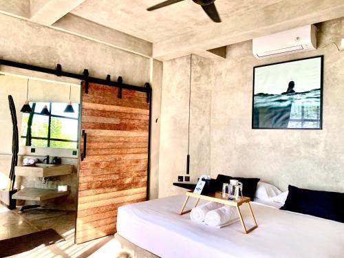 a bedroom with a white bed with a wooden wall at OCEANNA - Uluwatu, Bali in Uluwatu