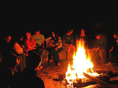 a group of people sitting around a fire at MALI Boutique Lodge & Tube 'n Axe Budget Accommodation in Stormsrivier