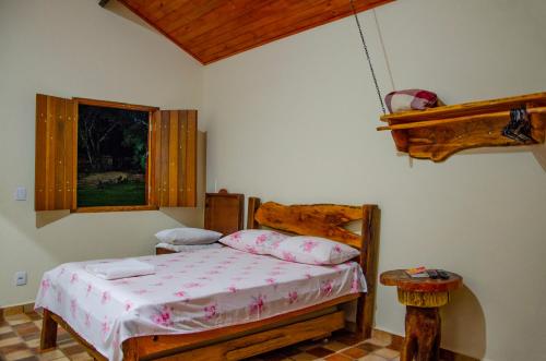 a bedroom with a bed and a window at Pousada Muro de Pedra in São Thomé das Letras