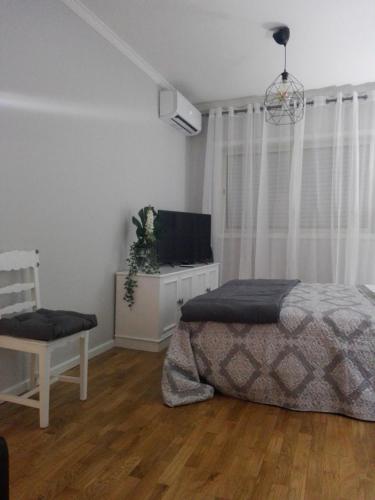 a bedroom with a bed and a tv and a chair at Secondlove in Porto