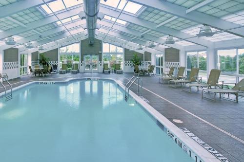 a large swimming pool in a building with tables and chairs at Holiday Inn Hotel & Suites Memphis-Wolfchase Galleria by IHG in Memphis