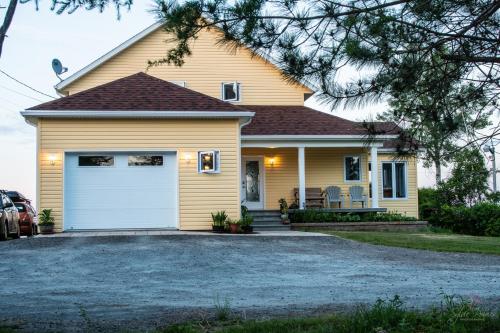 a yellow house with a white garage at Domaine sur une plage in Saint-Félicien
