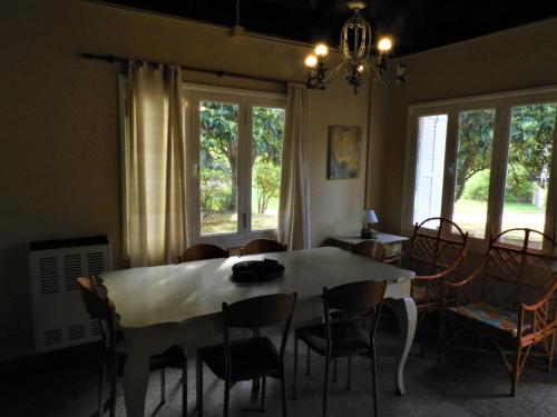 comedor con mesa, sillas y ventanas en Shanti-om en Sierra de la Ventana