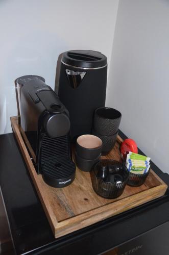 a coffee maker and cups on a wooden cutting board at Sjiek Basiliek in Oudenbosch