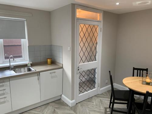 a kitchen with white cabinets and a table and a door at Fab City Centre Pad, walking distance to City Centre in Belfast
