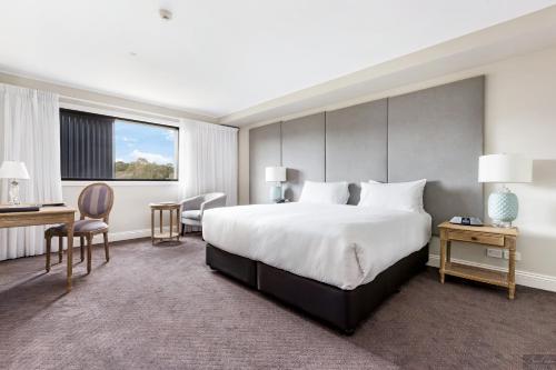 a hotel room with a large bed and a desk at Miramare Gardens Boutique Accommodation in Terrey Hills