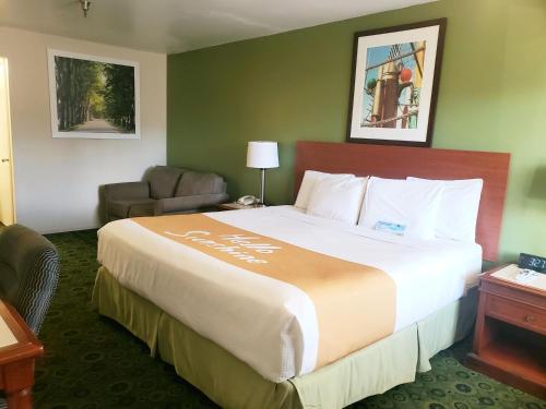a hotel room with a large bed and a chair at Days Inn by Wyndham Westley in Westley