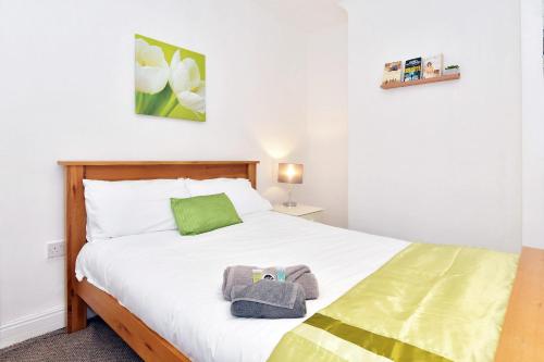 a bedroom with a bed with white sheets and a green pillow at Townhouse @ Hanley Road Stoke in Ford Green