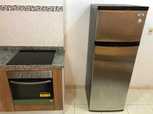 a stainless steel refrigerator in a kitchen next to a stove at WilMar Apart Hotel in Encarnación