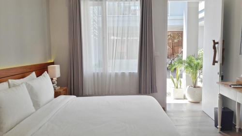a bedroom with a white bed and a large window at Mantra Gili in Gili Trawangan