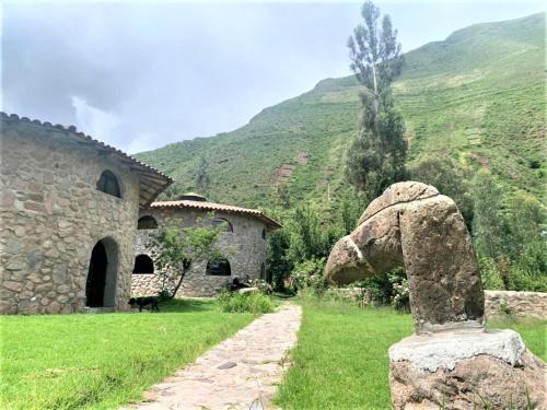 eine Steinstatue vor einem Gebäude und einem Berg in der Unterkunft Illa Wasi Sacred Valley in Urubamba