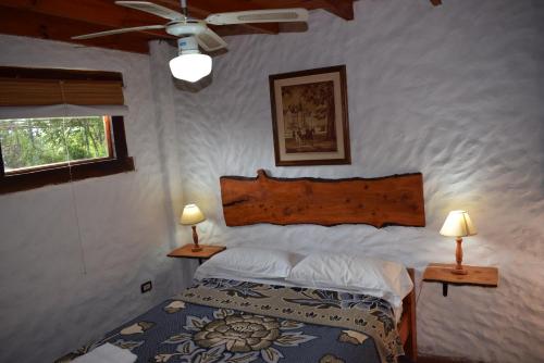 a bedroom with a bed and two lamps on tables at Cabañas La Rosada in Santa Rosa de Calamuchita