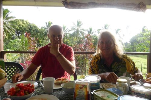 un uomo e una donna seduti a un tavolo con del cibo di JO's Farmstay-charming holiday farm close to famous Muri Beach a Rarotonga