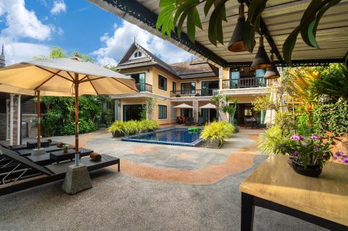 a house with a swimming pool and an umbrella at Private Villas Bangtao in Bang Tao Beach