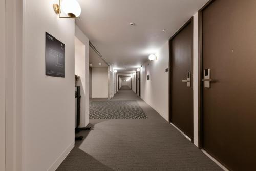 a corridor of a hallway with a long hallway at Vessel Inn Keisei Tsudanuma Station in Narashino