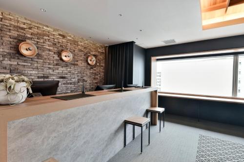 a bar with two stools and a brick wall at Vessel Inn Keisei Tsudanuma Ekimae in Narashino