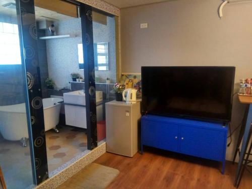 baño con una gran TV de pantalla plana en una cómoda azul en 悠然宅, en Tainan