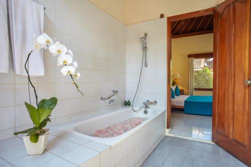 eine Badewanne mit Pflanze im Bad in der Unterkunft Puri Bagus Candidasa in Candidasa