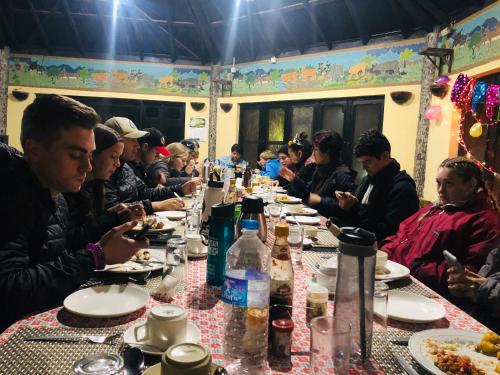 a group of people sitting at a long table eating food at Rhino Lodge Bardia Pvt Ltd in Bhurkīā