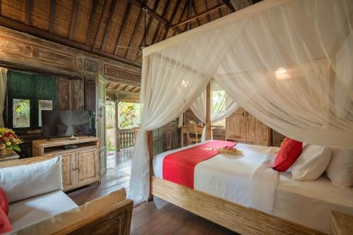 a bedroom with a canopy bed and a television at Villa Nini in Ubud