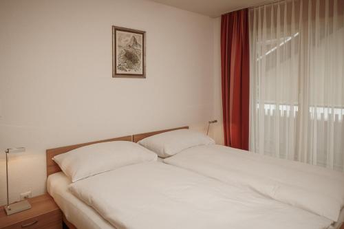 a white bed in a room with a window at Haus Mischabel in Zermatt