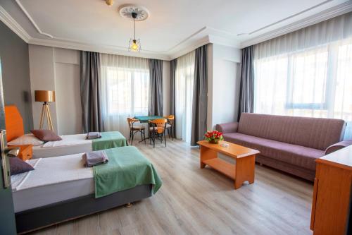 a hotel room with two beds and a couch and a table at HMA Hotel & Suites in Alanya