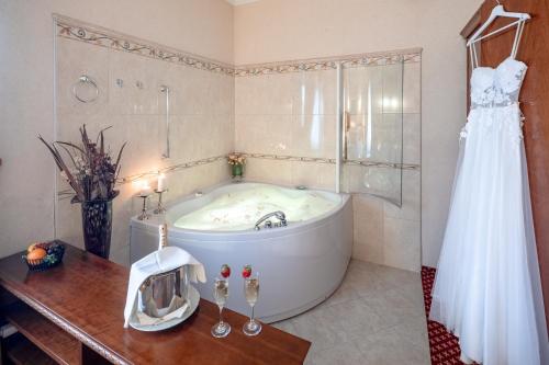 a wedding dress is hanging in a bathroom with a tub at Hotel Waldinger in Osijek