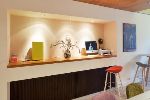 a waiting room with a counter with a computer and stools at Hotel The Neighbour's Magnolia in Amsterdam