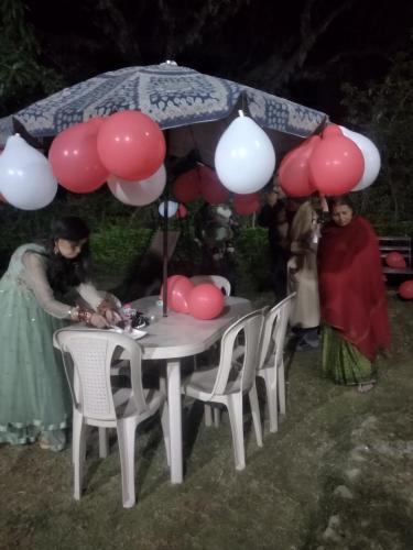 two women standing around a table with balloons and an umbrella at Oxygen Homestay-A Blissful Retreat in Dehradun