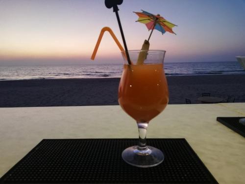 a drink sitting on a table next to the beach at Emerald Sea Resort in Ngwesaung