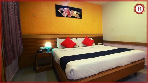a bedroom with a large bed with red pillows at Hotel RAKS in Thanjāvūr