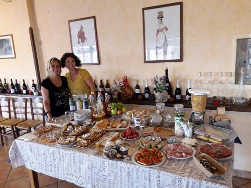 two women standing in front of a table with food at Agriturismo Torre Cristina in Aprilia