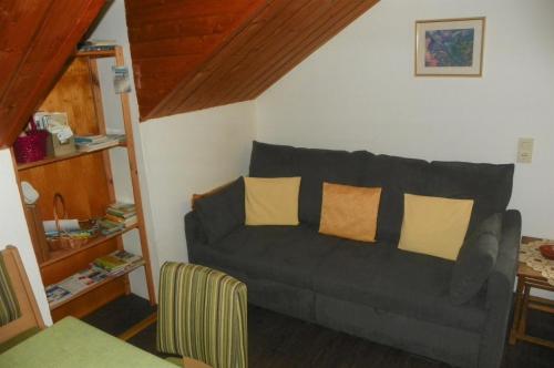 uma sala de estar com um sofá cinzento com almofadas amarelas em Ferienwohnung am Weissenstädter See em Weißenstadt