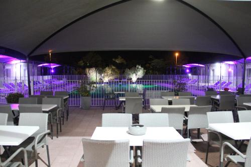 a restaurant with tables and chairs and purple lights at Hôtel Saint Louis in Le Thor