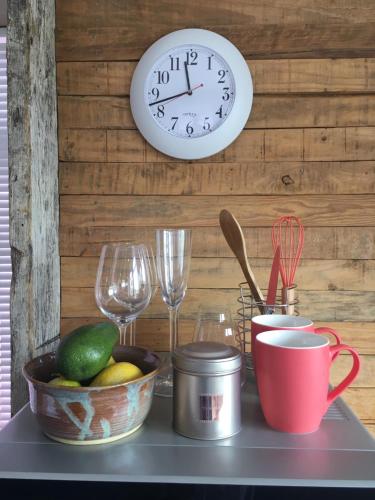 a clock on a wall next to a table with wine glasses at Kommetjie Heaven in Kommetjie