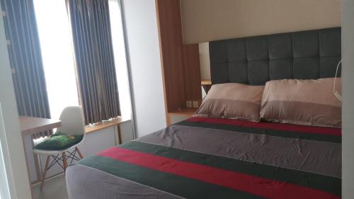 Un dormitorio con una cama y una silla y ventanas. en Ruby Apartment #1, en Yogyakarta