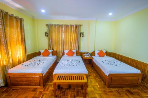 Habitación con 2 camas con almohadas de color naranja en Mother's Home Hotel, en Nyaung Shwe