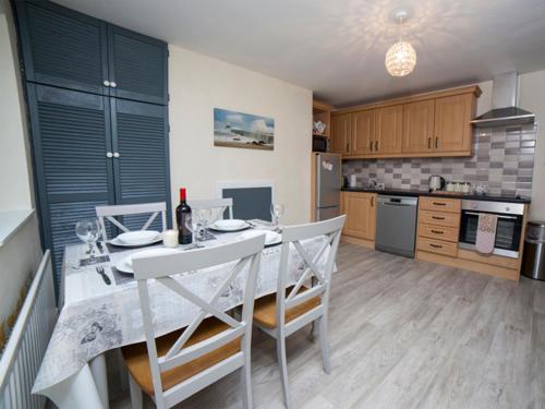 a kitchen with a white table and chairs and a kitchen with at Belmullet Townhouse in Belmullet