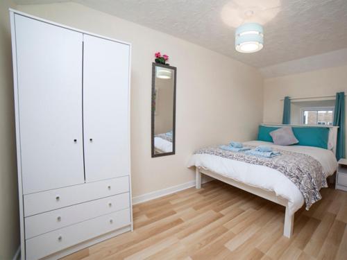 a bedroom with a bed with a dresser and a cabinet at Belmullet Townhouse in Belmullet