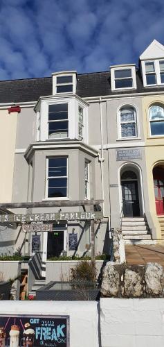 a white house with a sign in front of it at Rocky Cove Bed and Breakfast in Ilfracombe
