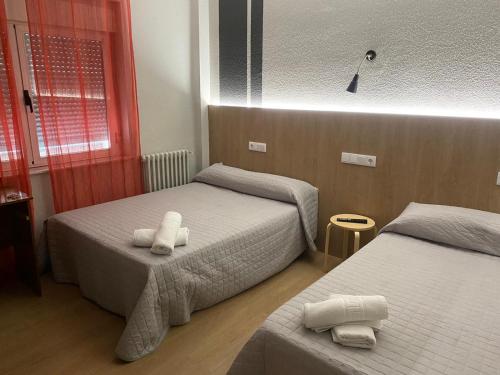 Habitación de hotel con 2 camas y toallas. en Hostal Uría, en Salamanca
