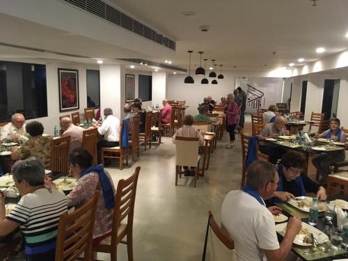 a group of people sitting at tables in a restaurant at The Hotel Canoe in Kannur