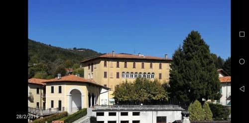 ein großes Gebäude mit einem Baum davor in der Unterkunft Residenza Santa Valeria in Caglio