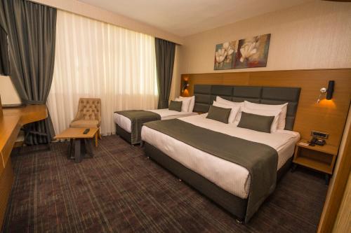ein Hotelzimmer mit 2 Betten und einem Schreibtisch in der Unterkunft New Garden Hotel in Diyarbakır