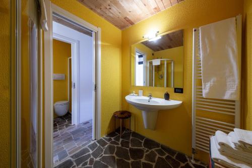 ボルカ・ディ・カドーレにあるChalet Dolomiti 430の黄色のバスルーム(シンク、鏡付)